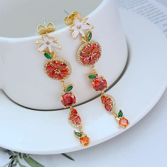 Earrings on a soft lemon yellow or fresh mint green background, showcasing the colorful cascade of fruit and flower charms. Alt: “Kate Spade Multicolour Flower Fruit Dangle Earrings – Enamel Fruit & Floral Jewelry.”