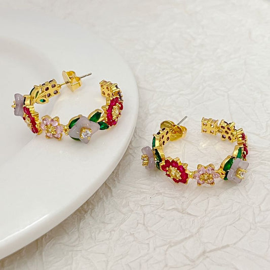 Earrings on a soft blush or garden green background, showcasing the cascading floral design along the hoop. Alt: “Kate Spade Bursting Blooms Hoop Earrings – Floral Crystal Enamel Jewelry.”