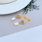Earrings on a soft sand-beige or seafoam green background, highlighting the warm pink conch pearl and gold setting. Alt: “Kate Spade New York Conch Pearl Gold Tone Earrings – Shell Pearl Drop Jewelry.”