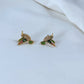 Earrings on a soft sage green or misty blue background, showcasing the hummingbird charm with iridescent enamel wings. Alt: “Kate Spade New York Hummingbird Earrings – Enamel Bird Drop Jewelry.”