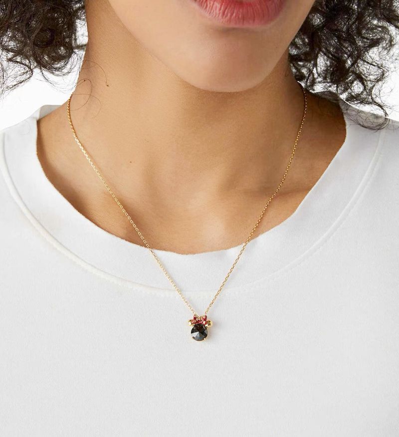  Necklace photographed alongside subtle Disney elements (like polka dots, a vintage Minnie figurine, or a classic red bow) for thematic appeal. Alt: “A Nod to Nostalgia: Styling the Kate Spade Minnie Slider Necklace.”