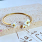 Cuff on a soft cream or dusty rose background, showcasing the purple and gold pansy enamel detail. Alt: “Kate Spade New York Precious Pansy Enamel Cuff – Purple Floral Bracelet.”