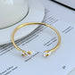Cuff on a soft cream or dusty rose background, showcasing the purple and gold pansy enamel detail. Alt: “Kate Spade New York Precious Pansy Enamel Cuff – Purple Floral Bracelet.”
