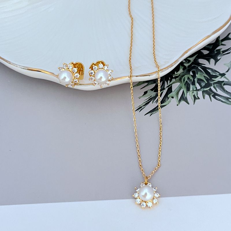Necklace on a soft, bright background (light blue or creamy white), highlighting the sun pendant's pearl center and crystal halo. Alt: “Kate Spade Sunny Pave & Imitation Pearl Halo Necklace – Radiant Sun Motif Jewelry.”