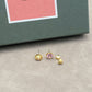 Three gold earrings with different gemstones on a gray surface.