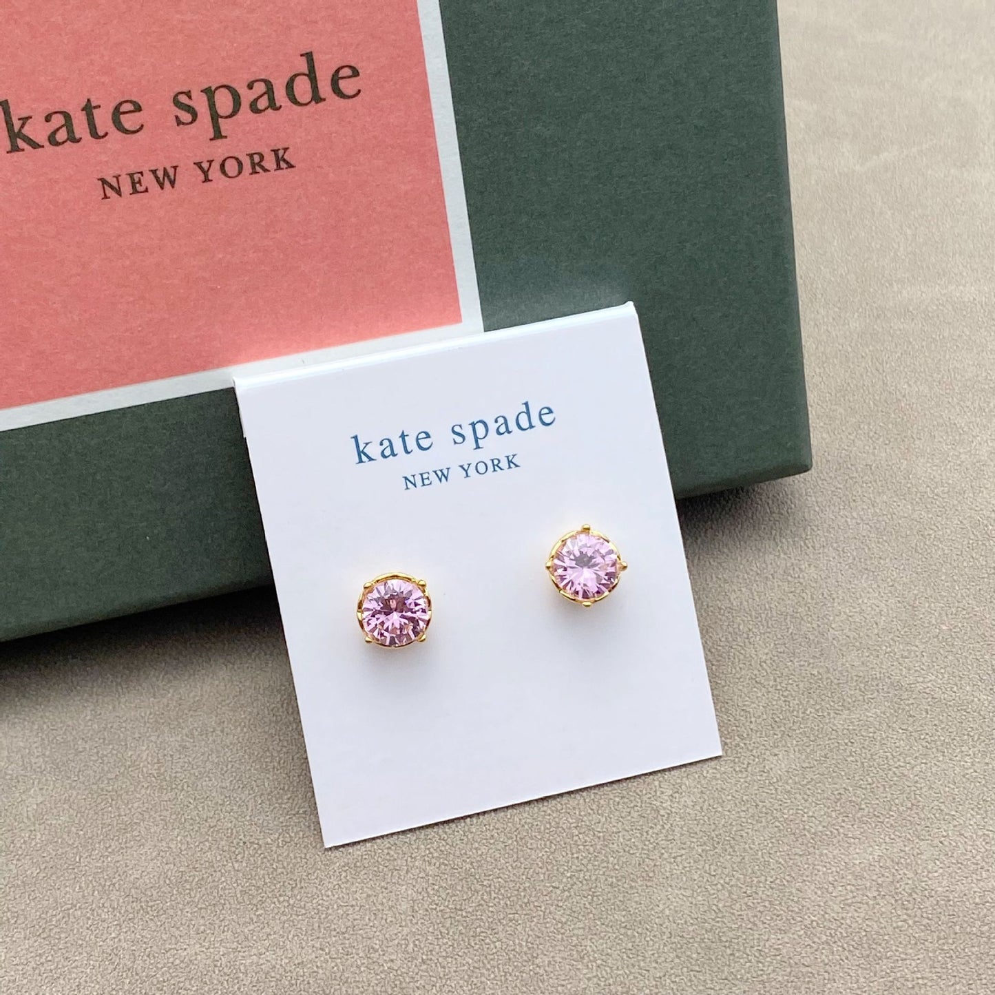 Pink earrings on a Kate Spade New York card with a green box in the background