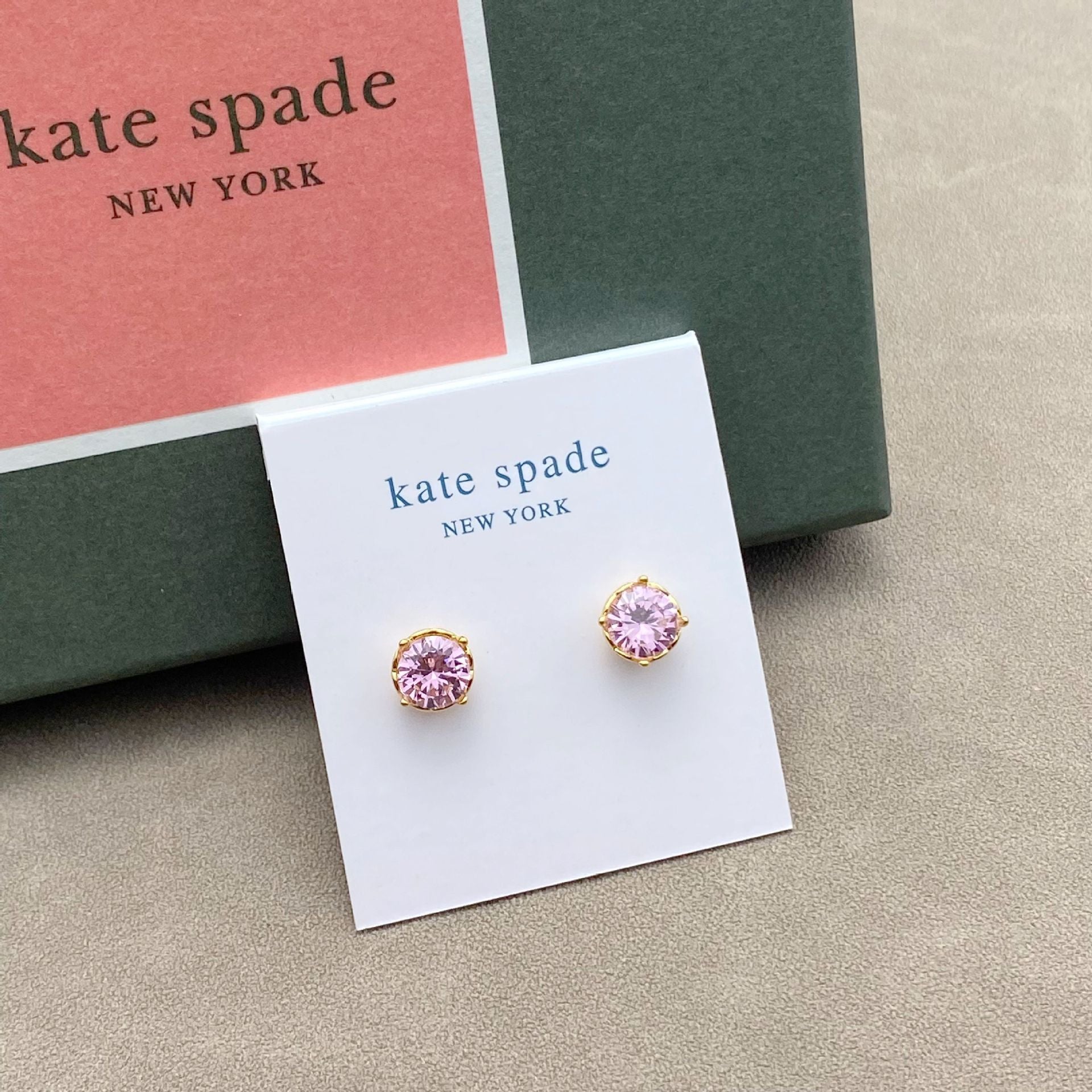 Pink earrings on a Kate Spade New York card with a green box in the background