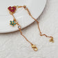 Bracelet displayed on a soft moss green or linen background, highlighting the mix of floral and leaf charms. Alt: “Kate Spade Yellow Gold Plated Flowers & Plants Bracelet – Botanical Charm Jewelry.”