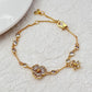 Bracelet displayed on a soft moss green or linen background, highlighting the mix of floral and leaf charms. Alt: “Kate Spade Yellow Gold Plated Flowers & Plants Bracelet – Botanical Charm Jewelry.”