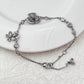 Bracelet displayed on a soft moss green or linen background, highlighting the mix of floral and leaf charms. Alt: “Kate Spade Yellow Gold Plated Flowers & Plants Bracelet – Botanical Charm Jewelry.”