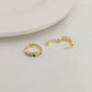 Gold hoop earrings with colorful gemstones on a light gray surface.