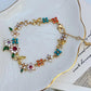 Bracelet displayed on a soft linen or weathered wood background, evoking a rustic, pastoral feel. Alt: “Kate Spade Pastoral Style Floral Bracelet – Enamel Flower Charm Jewelry.”