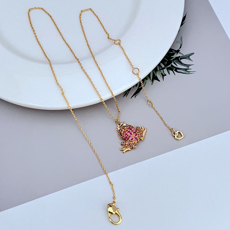 Necklace displayed on a soft green or natural-toned background, highlighting the frog pendant’s shape and crystal details. Alt: “Kate Spade Pave Frog Drop Pendant Necklace – Whimsical Crystal Animal Jewelry.”