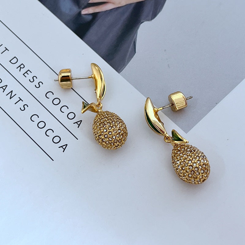 Earrings displayed side by side on a soft linen or farmers' market-inspired background, showcasing the mismatched pear and lemon charms. Alt: “Kate Spade Pear Lemon Earrings – Enamel Citrus & Pear Drop Jewelry.”