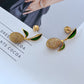 Earrings displayed side by side on a soft linen or farmers' market-inspired background, showcasing the mismatched pear and lemon charms. Alt: “Kate Spade Pear Lemon Earrings – Enamel Citrus & Pear Drop Jewelry.”