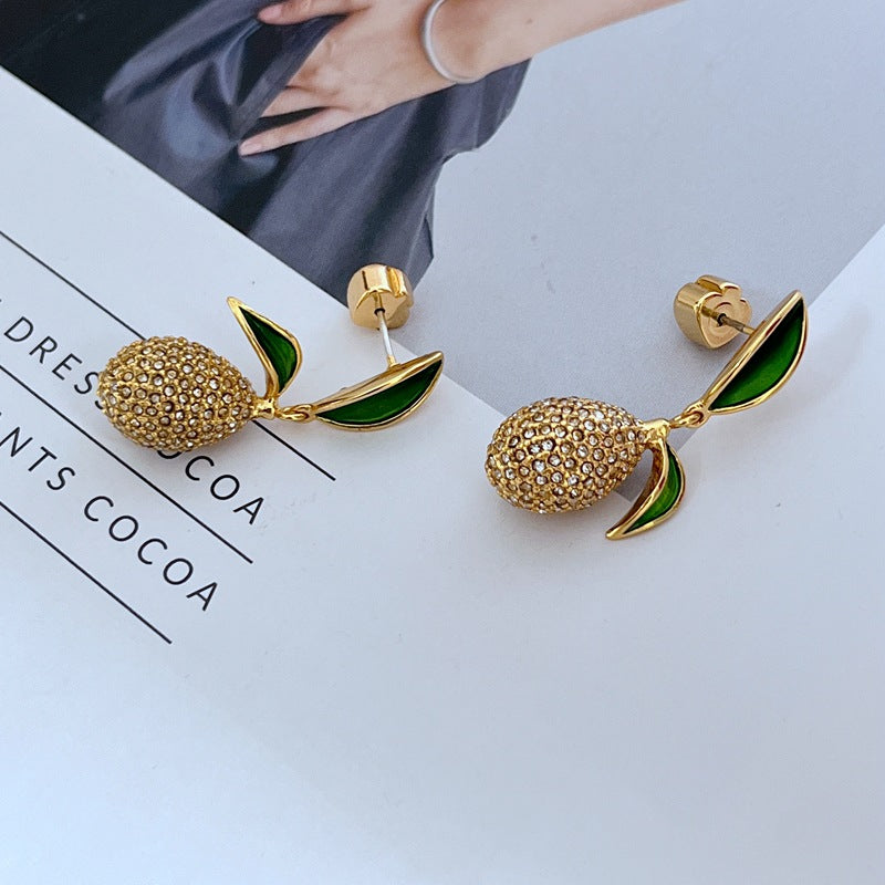 Earrings displayed side by side on a soft linen or farmers' market-inspired background, showcasing the mismatched pear and lemon charms. Alt: “Kate Spade Pear Lemon Earrings – Enamel Citrus & Pear Drop Jewelry.”