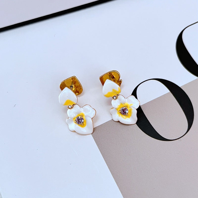  Earrings on a soft lavender or cream background, showcasing the purple and gold pansy blooms with delicate drop findings. Alt: “Kate Spade Precious Pansy Drop Earrings – Enamel Pansy Flower Jewelry.”
