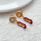  Earrings displayed side by side on a soft blush or cream background, showcasing the red heel and antique clock charms. Alt: “Kate Spade Red Heels and Clock Earrings – Whimsical Mismatched Jewelry Gift for Her.”

