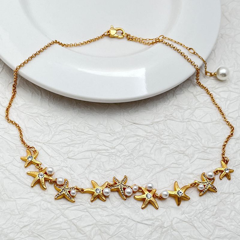 Necklace laid flat on a sandy-beige or light blue background, emphasizing the starfish pendant's shape and detail. Alt: “Kate Spade Sea Star Necklace – Delicate Starfish Pendant Jewelry.”