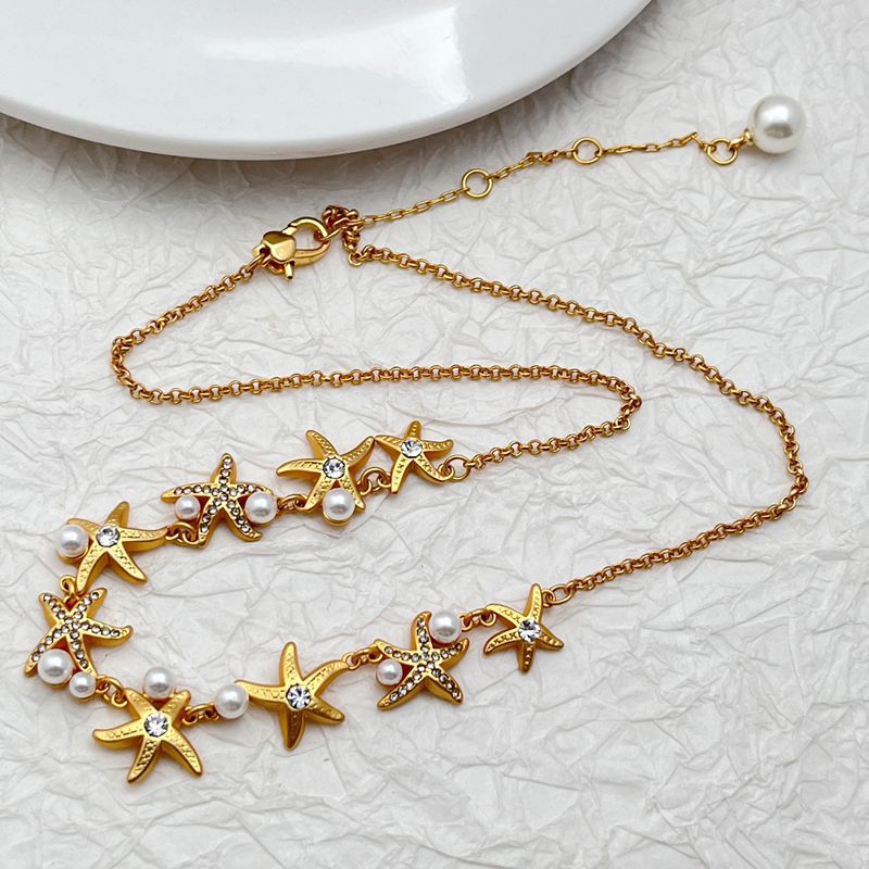 Necklace laid flat on a sandy-beige or light blue background, emphasizing the starfish pendant's shape and detail. Alt: “Kate Spade Sea Star Necklace – Delicate Starfish Pendant Jewelry.”