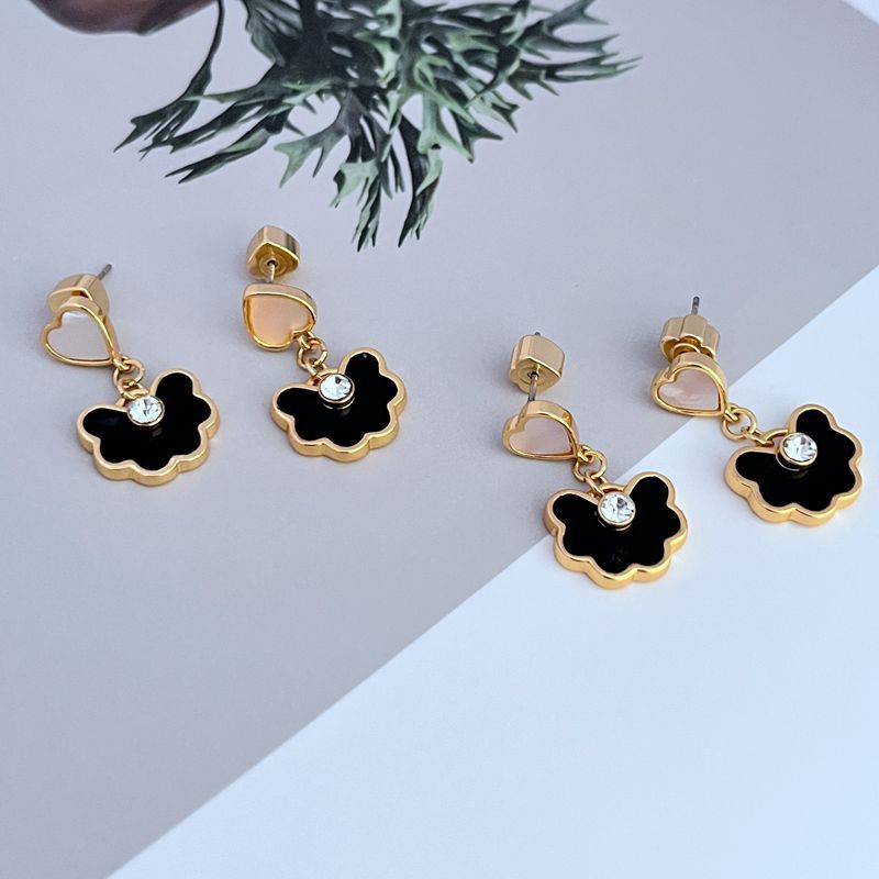 Earrings on a soft blush pink or cream background, showcasing the spade-shaped floral pendant with enamel detailing. Alt: “Kate Spade Spade Flower Drop Earrings – Signature Floral Enamel Jewelry.”