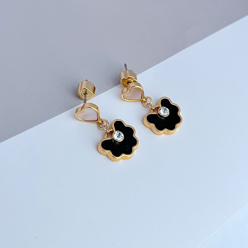 Earrings on a soft blush pink or cream background, showcasing the spade-shaped floral pendant with enamel detailing. Alt: “Kate Spade Spade Flower Drop Earrings – Signature Floral Enamel Jewelry.”