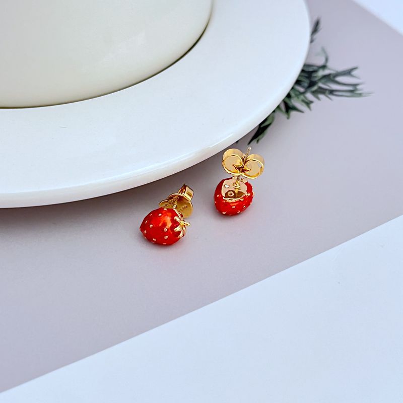 Earrings on a soft cream or blush pink background, highlighting the glossy red strawberry and gold finish. Alt: “Kate Spade Strawberry Fields Stud Gold Earrings – Enamel Fruit Jewelry New.”