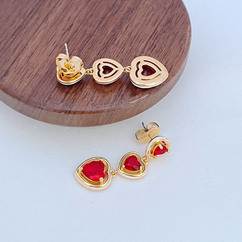 Macro shot focused on one of the heart charms and the fine chain links, highlighting the polished finish.