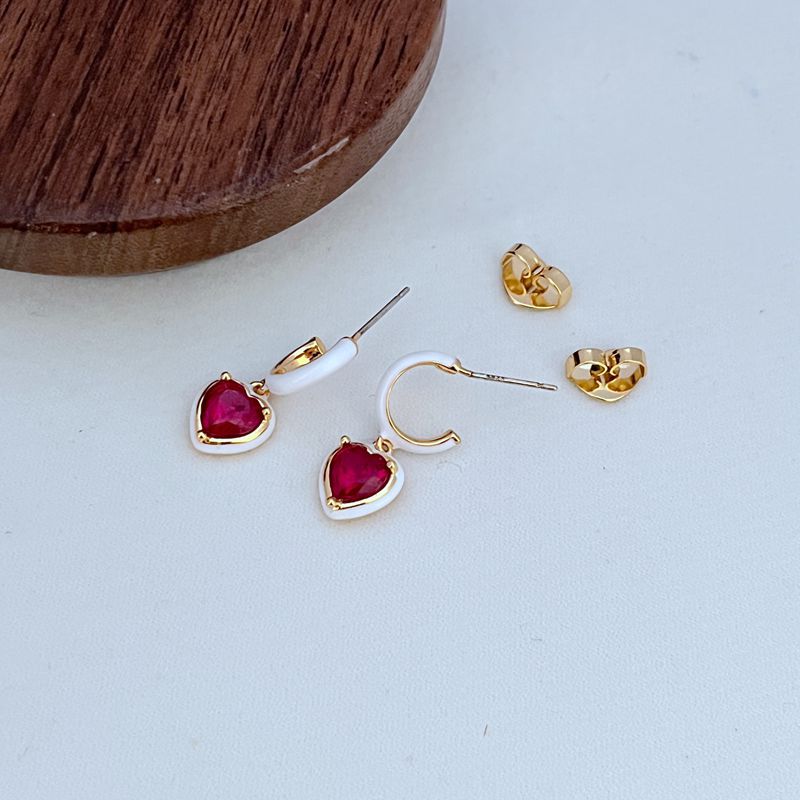 Macro shot focused on one of the heart charms and the fine chain links, highlighting the polished finish.