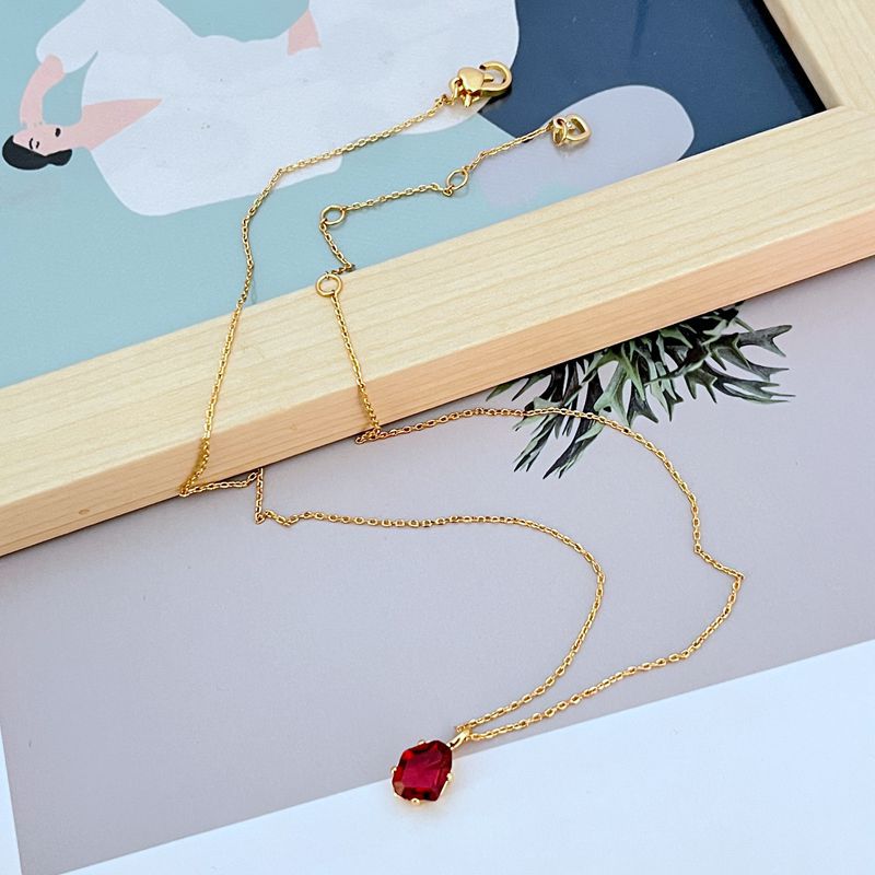 Necklace displayed on a dark background (navy or charcoal) to make the gold and fuchsia gemstone pop. Alt: “Kate Spade Treasure Trove Gold Necklace with Fuchsia Gem – Bold Statement Pendant.”