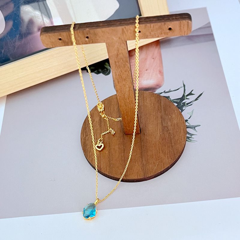 Necklace displayed on a dark background (navy or charcoal) to make the gold and fuchsia gemstone pop. Alt: “Kate Spade Treasure Trove Gold Necklace with Fuchsia Gem – Bold Statement Pendant.”