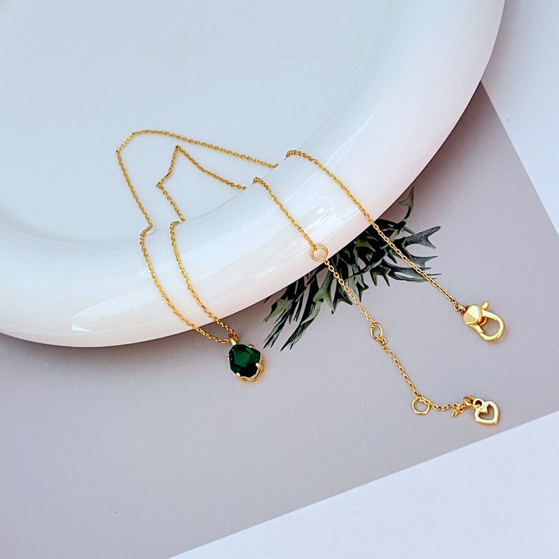 Necklace displayed on a dark background (navy or charcoal) to make the gold and fuchsia gemstone pop. Alt: “Kate Spade Treasure Trove Gold Necklace with Fuchsia Gem – Bold Statement Pendant.”