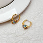 Earrings on a soft aquatic blue or seafoam green background, showcasing the gold huggie hoop with dangling enamel fish charm. Alt: “Kate Spade What A Catch Fish Huggie Earrings NEW – Gold Fish Hoop Jewelry.”