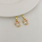 Gold hoop earrings with pink accents and clear gemstones on a light gray background