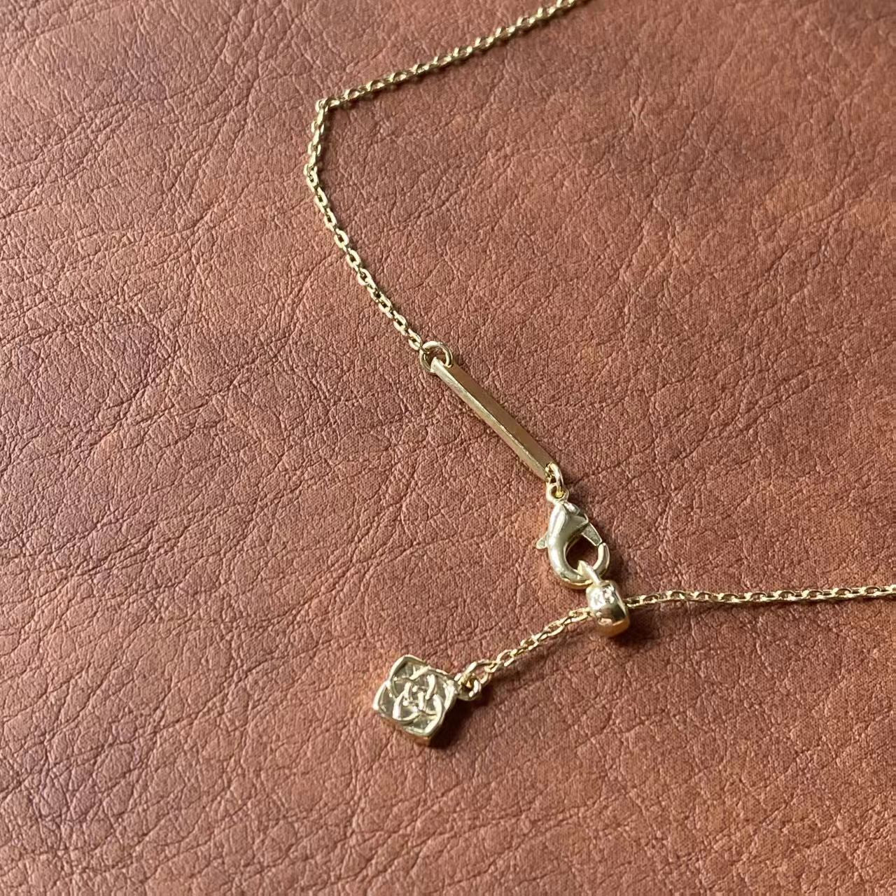 Gold necklace with a pendant on a brown leather surface