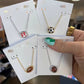 Four necklaces on display cards held by a hand with a blurred background