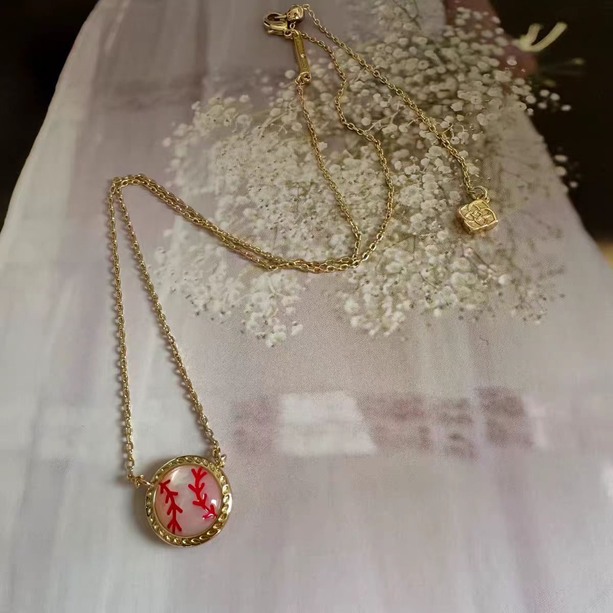 Gold necklace with a red pendant on a white fabric background