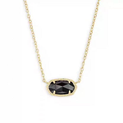 Gold necklace with a black gemstone pendant on a white background