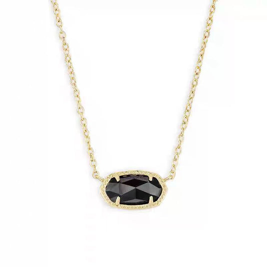Gold necklace with a black gemstone pendant on a white background