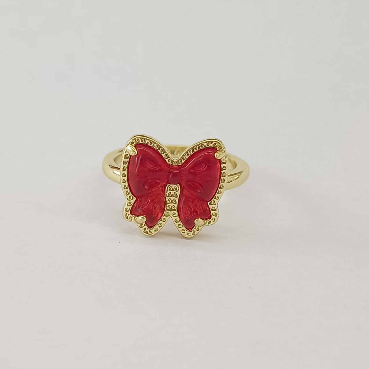 Clean shot of the ring on a finger or ring stand, showcasing the bow detail and the band against a neutral background.