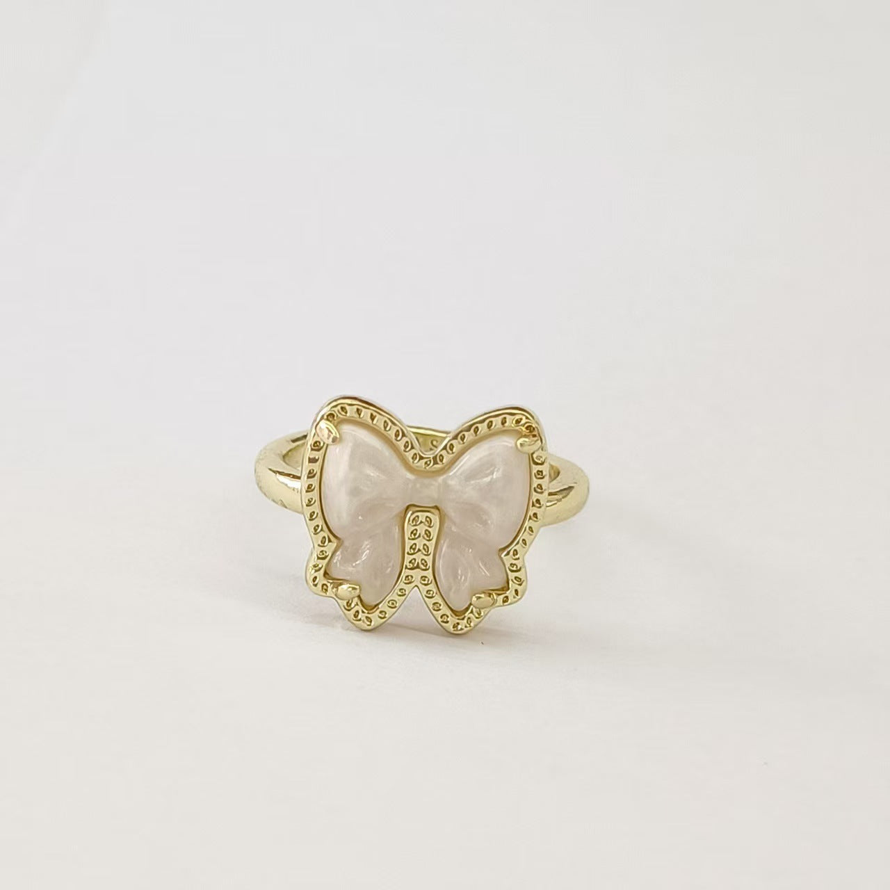 Clean shot of the ring on a finger or ring stand, showcasing the bow detail and the band against a neutral background.