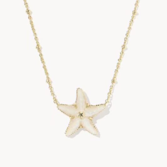 A delicate gold chain necklace featuring a textured cream starfish pendant with a small central gold bead, set against a clean off-white background.