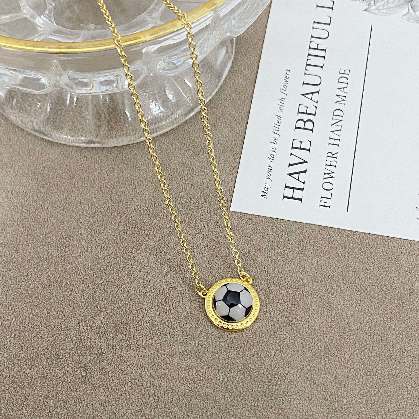 Gold necklace with a pendant on a beige surface