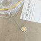 ZERRA Kendra Scott gold volleyball short pendant necklace hanging on a chain, close-up of the jewelry piece.