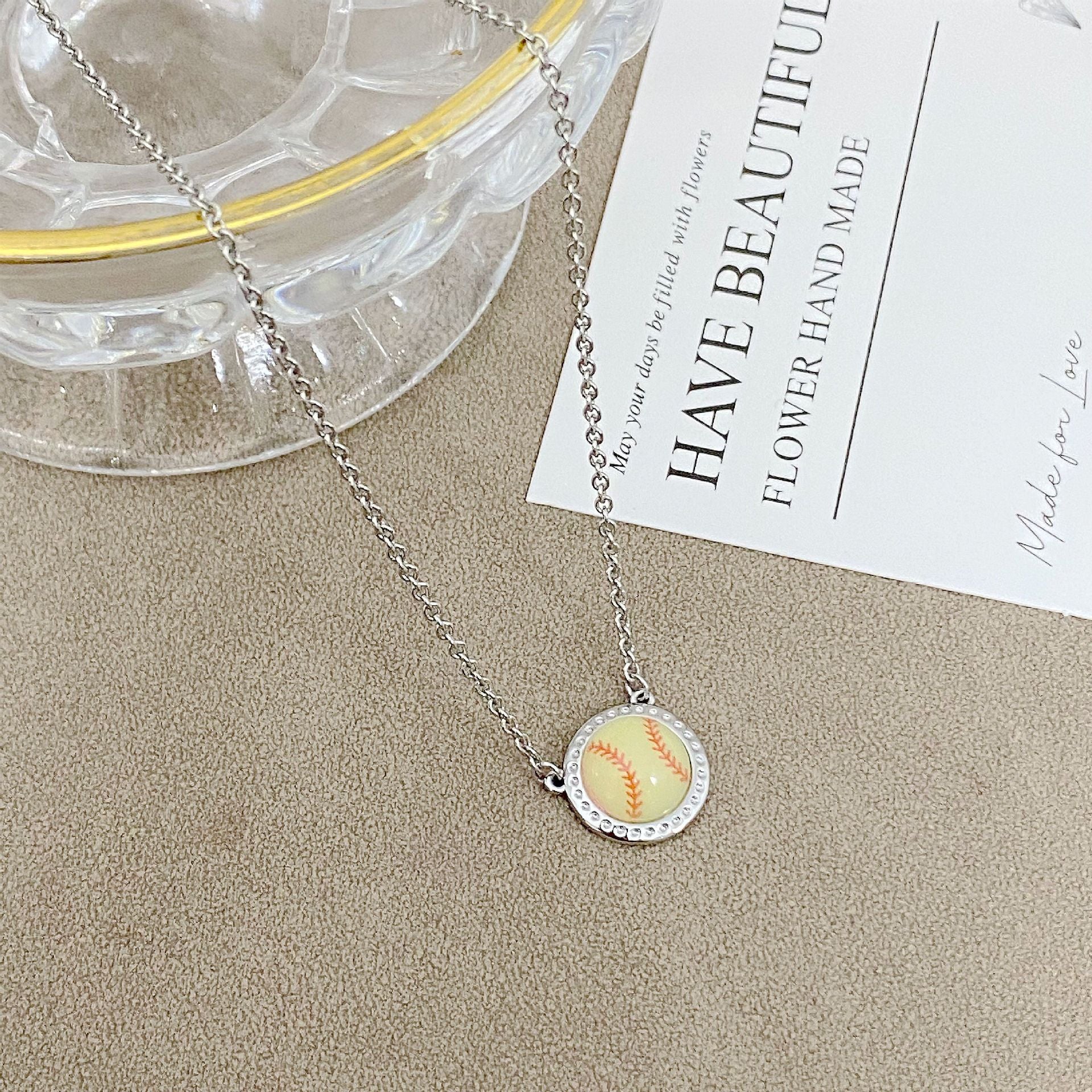 ZERRA Kendra Scott gold volleyball short pendant necklace hanging on a chain, close-up of the jewelry piece.