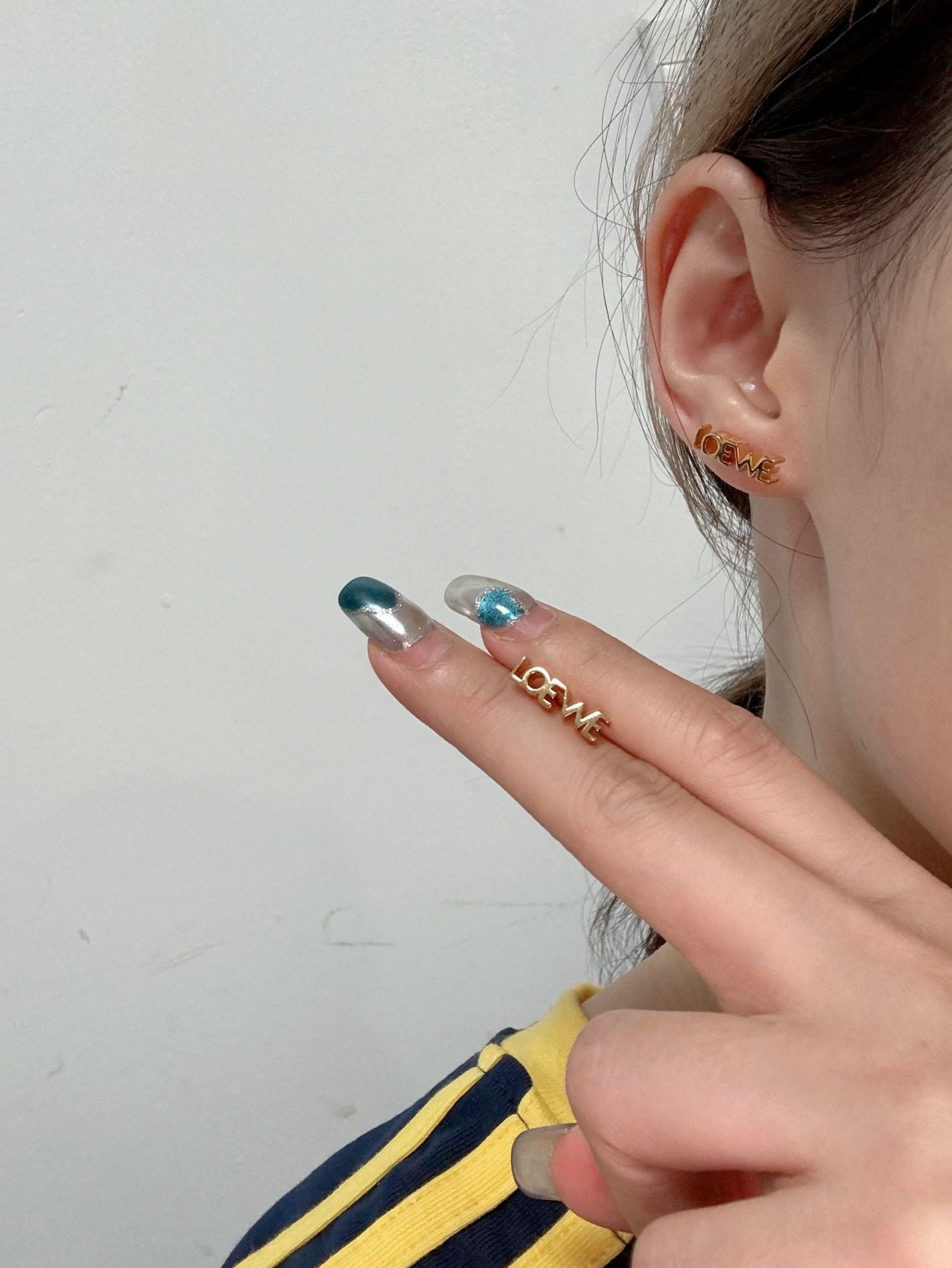 The earring displayed on a stand like a sculpture or next to abstract art, reinforcing its status as a collectible design object.