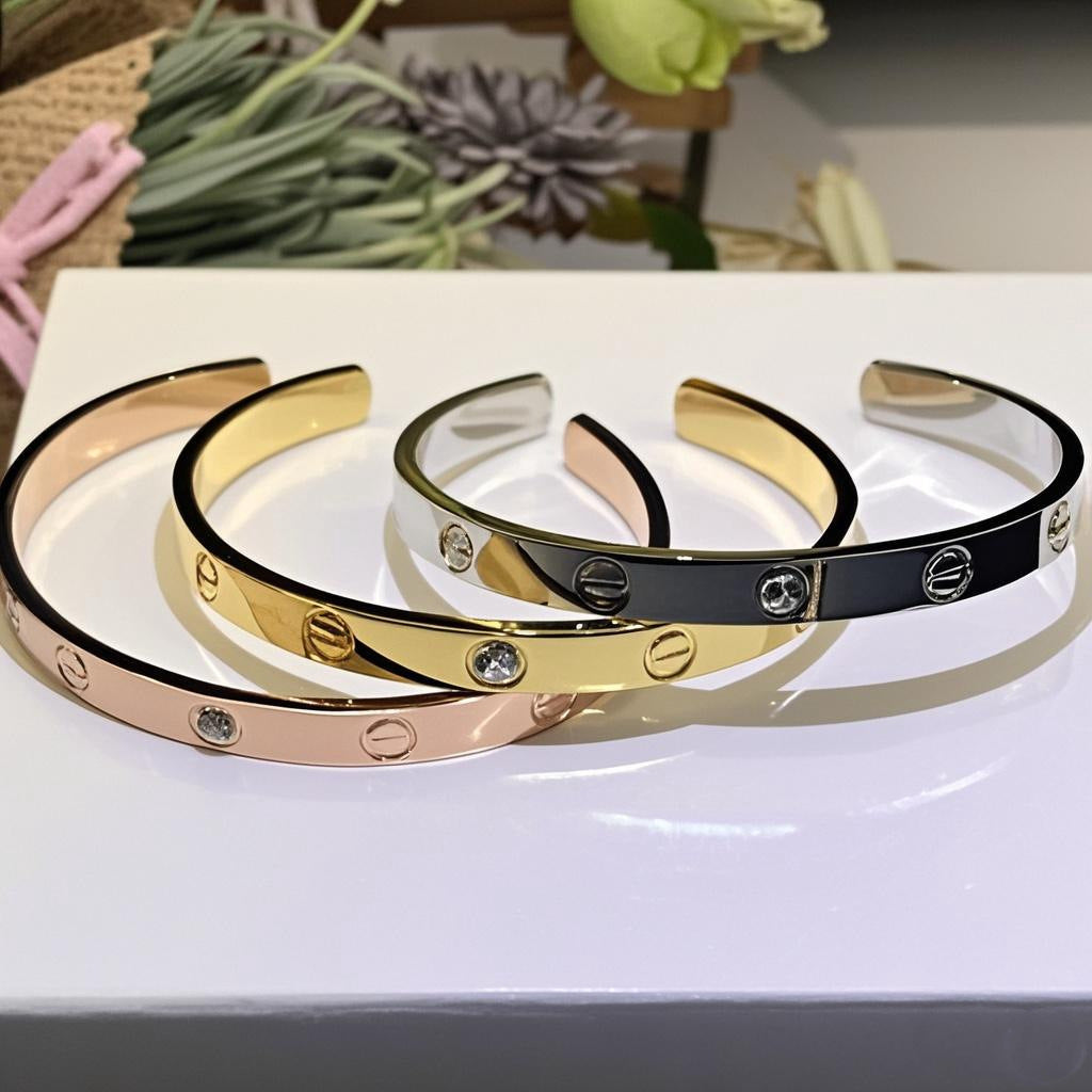 LOVE Bangle Bracelet | 18K Gold-Plated Sterling Silver Three gold, rose gold, and black bangles on a white surface with a blurred background.