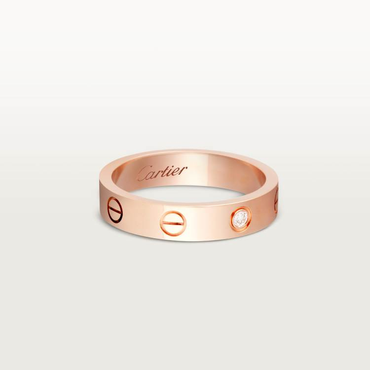 Rose gold Cartier ring with a diamond on a light gray background