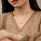 Woman wearing a gold necklace with a detailed pendant, blurred background