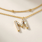 Angle: Straight-on to clearly showcase the two different chain lengths and the letter "M" pendants at their respective positions.